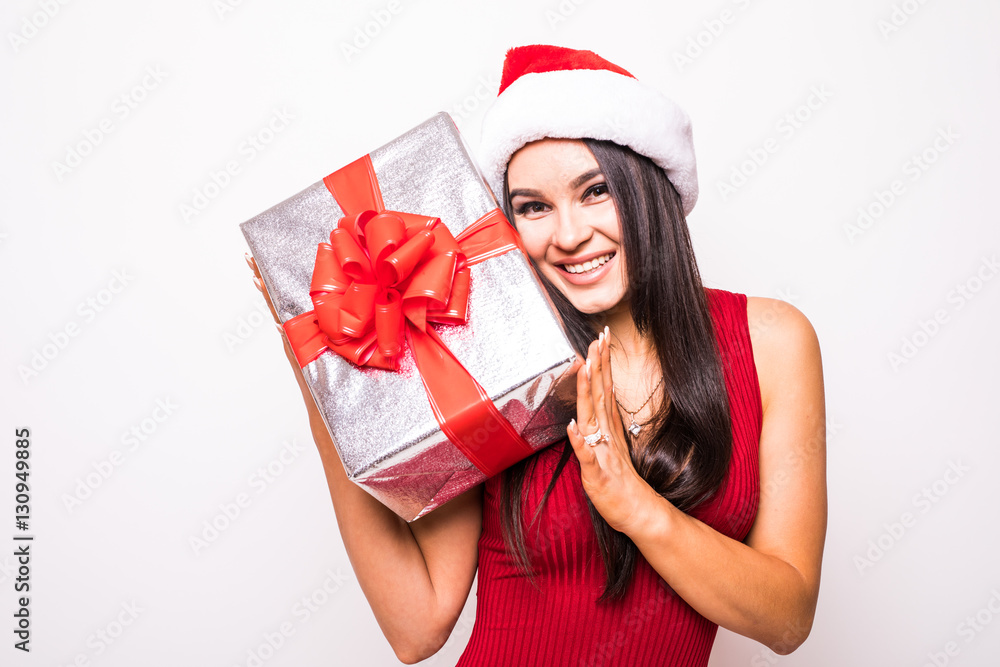 Young woman in red dress with santa hat hold Christmas gift over white background Young woman in red dress with santa hat hold Christmas gift over white background