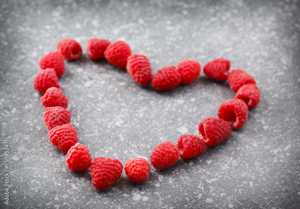 Raspberries in a heart shape on a stone background Raspberries in a heart shape on a stone background