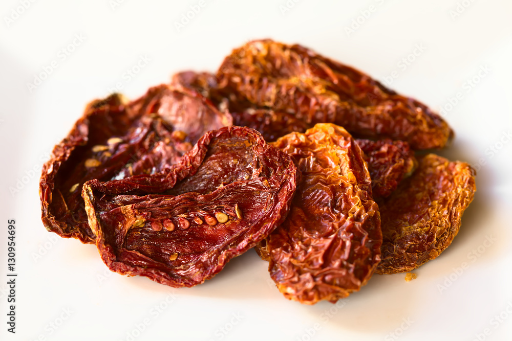 Sun-dried tomato halves on white plate, photographed with natural light (Selective Focus, Focus in the middle of the image)