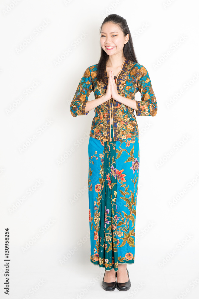 Southeast Asian woman in batik dress greeting Southeast Asian woman in batik dress greeting