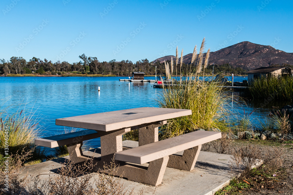 Obraz premium Picnic table at Lake Murray in San Diego, California with boat rental dock and Cowles Mountain in the background, 