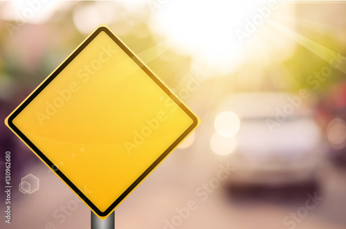 Empty yellow traffic sign on blur traffic road with colorful bokeh light abstract background.