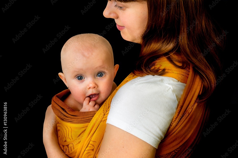 Happy mother with her baby in a sling isolated on balck foto de Stock