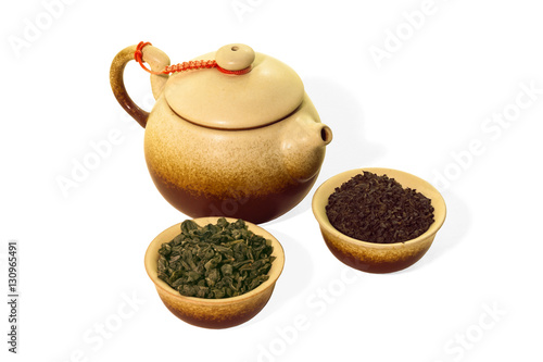 Ceramic teapot and two cups with dry tea close-up on a white background isolated.