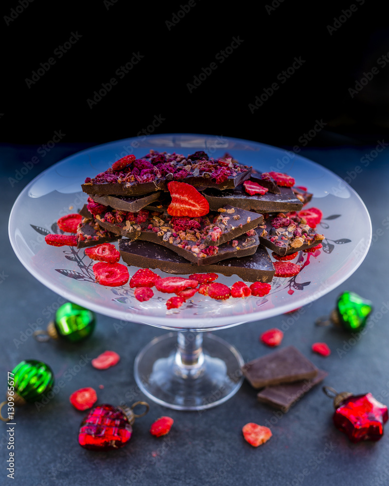 Dessert dark chocolate with dried raspberries and strawberries with Christmas decoration on a stone background. 