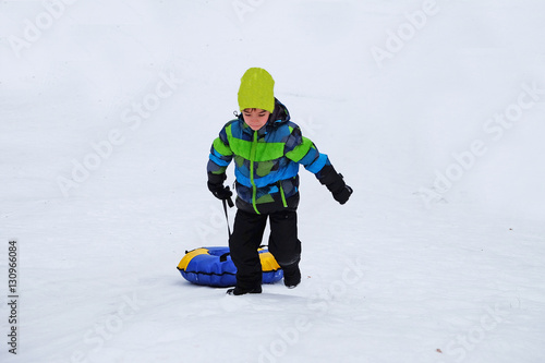 European boy tugs at the inflatable slide (snow) sledge
