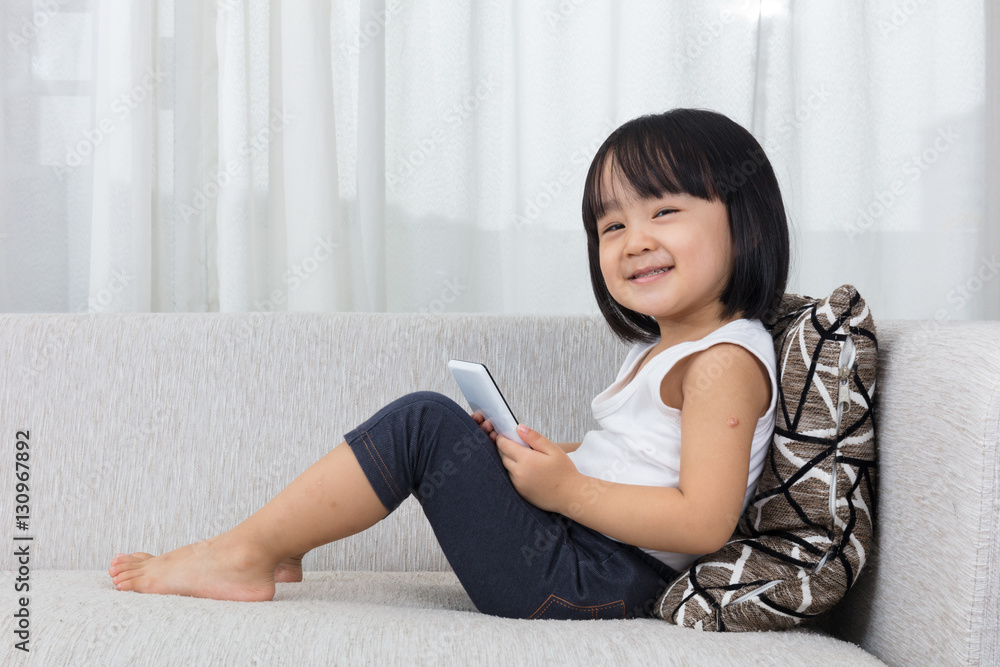 Asian Chinese little girl lying on the sofa with phone Asian Chinese little girl lying on the sofa with phone