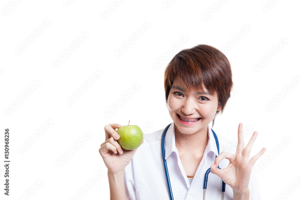 Young Asian female doctor show OK with apple. Young Asian female doctor show OK with apple.