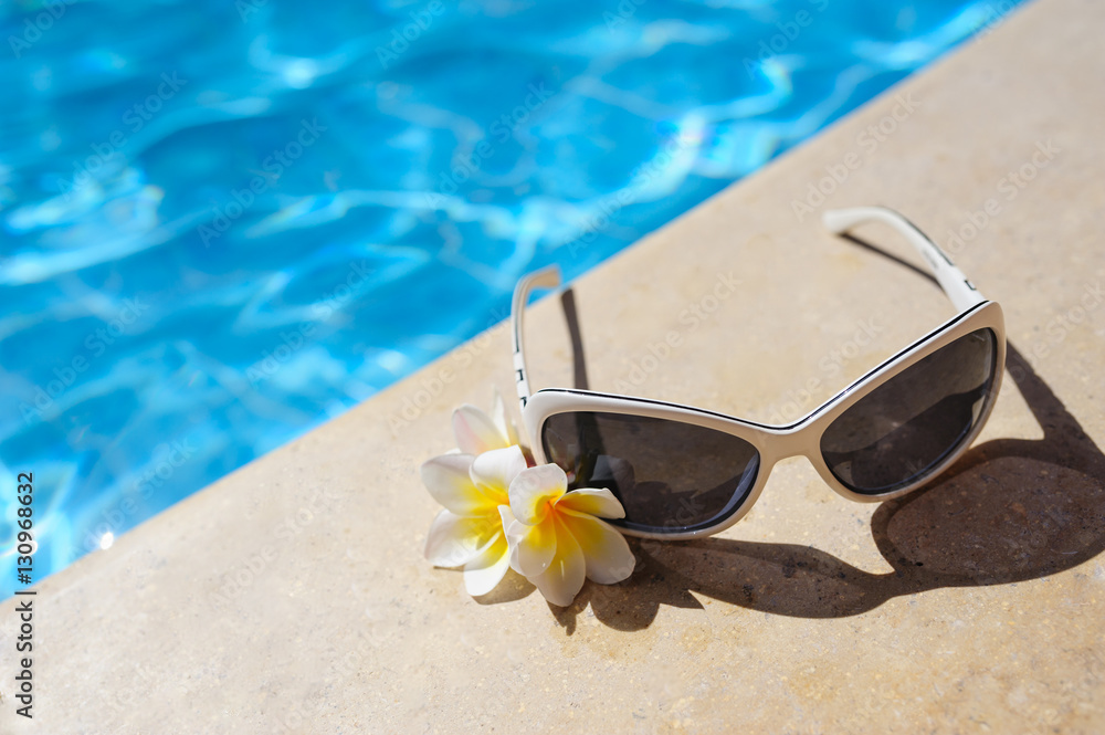 sunglasses and white flowers of bougainvillea near pool