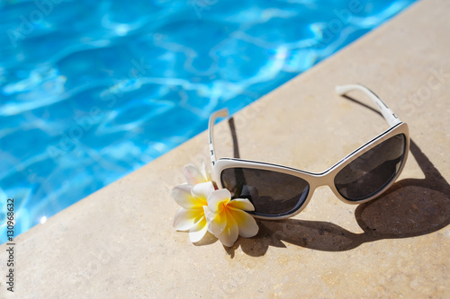 sunglasses and white flowers of bougainvillea near pool