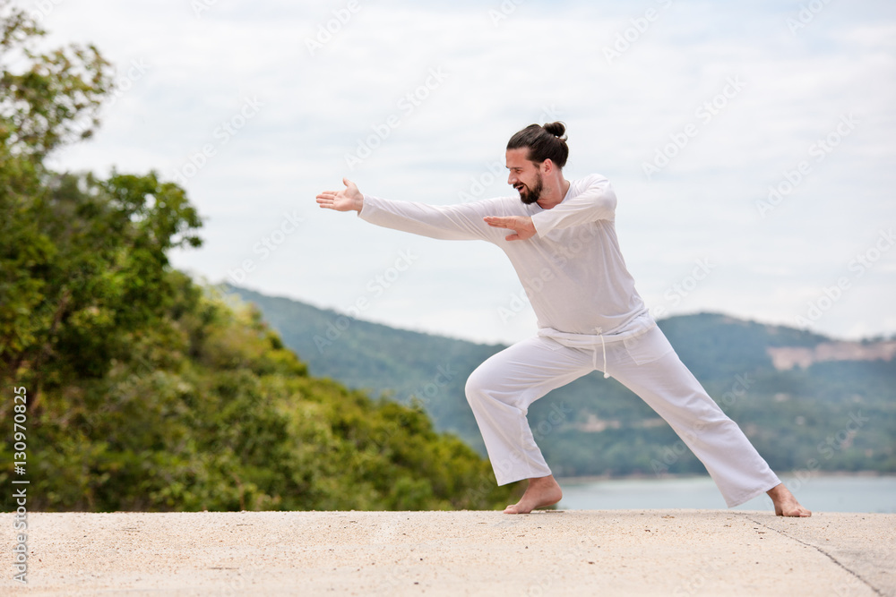 Kickboxer or muay thai fighter Man in white training karate  Wushu on mountain