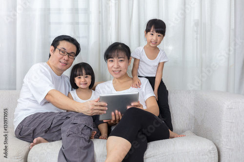 Happy Asian Chinese family using tablet on the couch