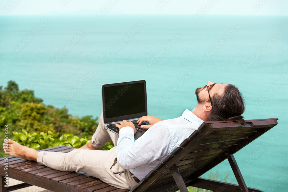 Businessman wearing a suit using laptop on the beach