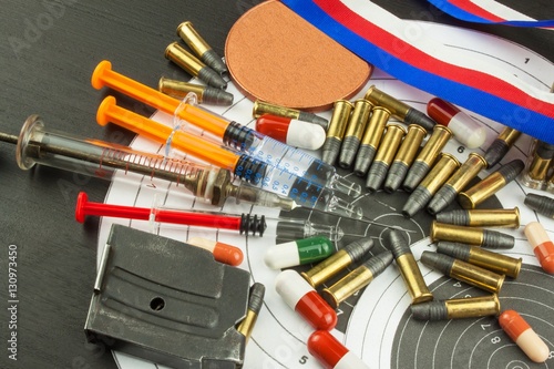 Syringe and medals. Doping in shooting sport. Abuse of anabolic steroids for sports. Deception in biathlon. The International Federation of biathlon - IBU. Ammunition and winners medals.
