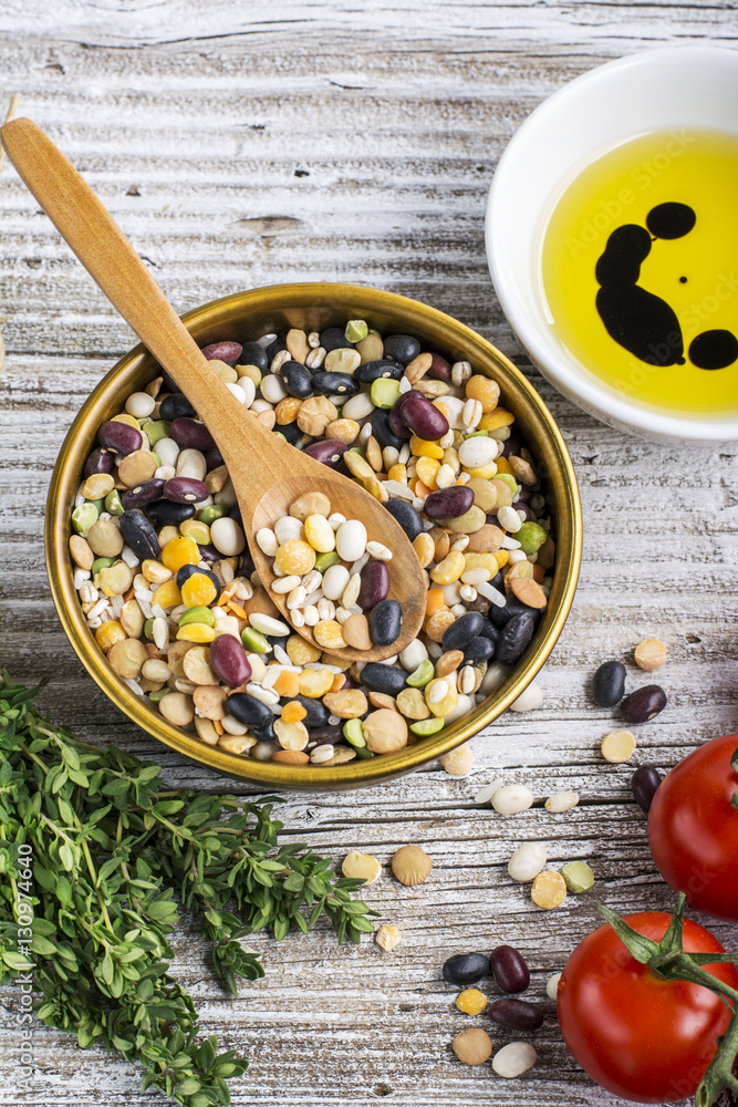 Assorted legumes grains on a light background with ripe tomatoes, olive oil, herbs, pepper ingredients for lunch or dinner. Top view. The concept of healthy home-cooked meal. Assorted legumes grains on a light background with ripe tomatoes, olive oil, herbs, pepper ingredients for lunch or dinner. Top view. The concept of healthy home-cooked meal.
