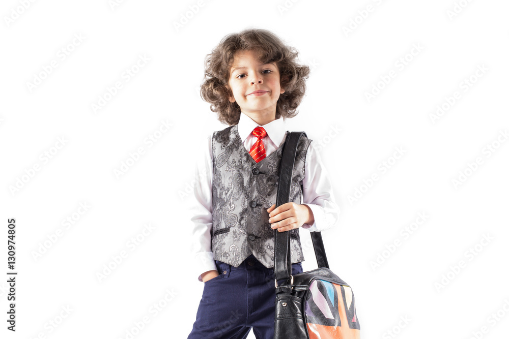 Funny curly boy stands in a waistcoat with a bag over his shoulder. White background. Funny curly boy stands in a waistcoat with a bag over his shoulder. White background.