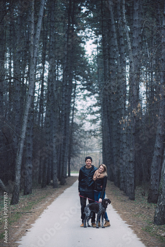 Loving couple in forest with cute dog. Happy couple in love posing outdoor.