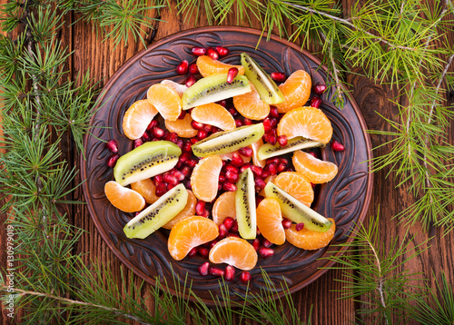Fresh fruit salad: kiwi, tangerine, pomegranate. Christmas theme