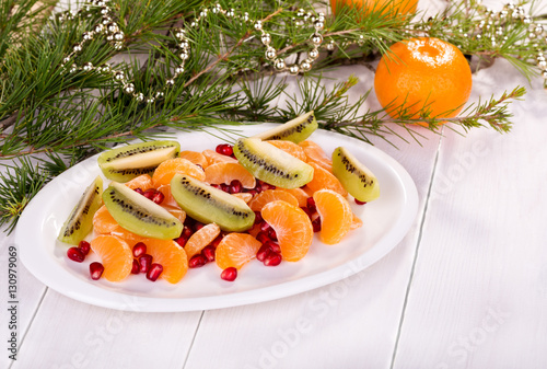 Fresh fruit salad: kiwi, tangerine, pomegranate. Christmas theme