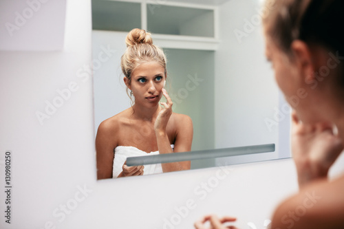 Beautiful young woman applying cosmetic cream