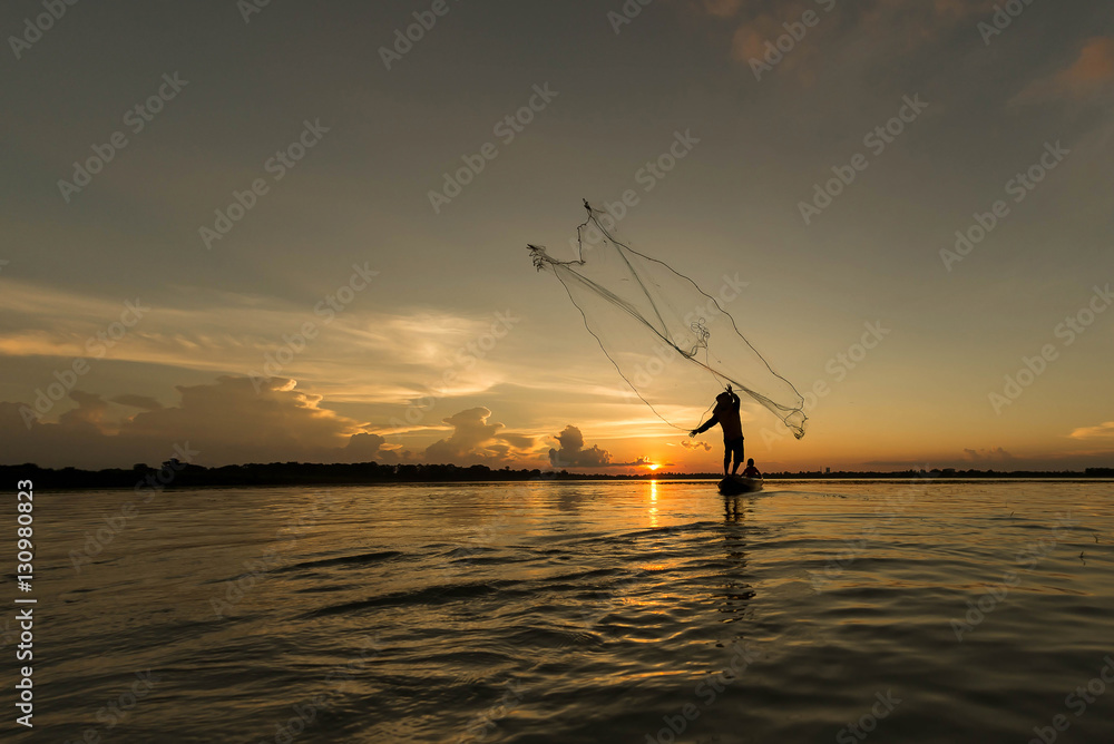 Silhouette of fisherman throwing net for fishing on the lake