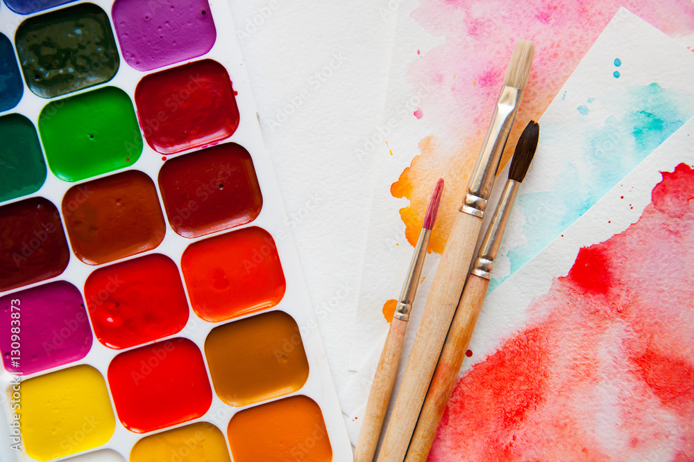 Naklejka premium Top view Palette of watercolor paints, brushes and paper for a w