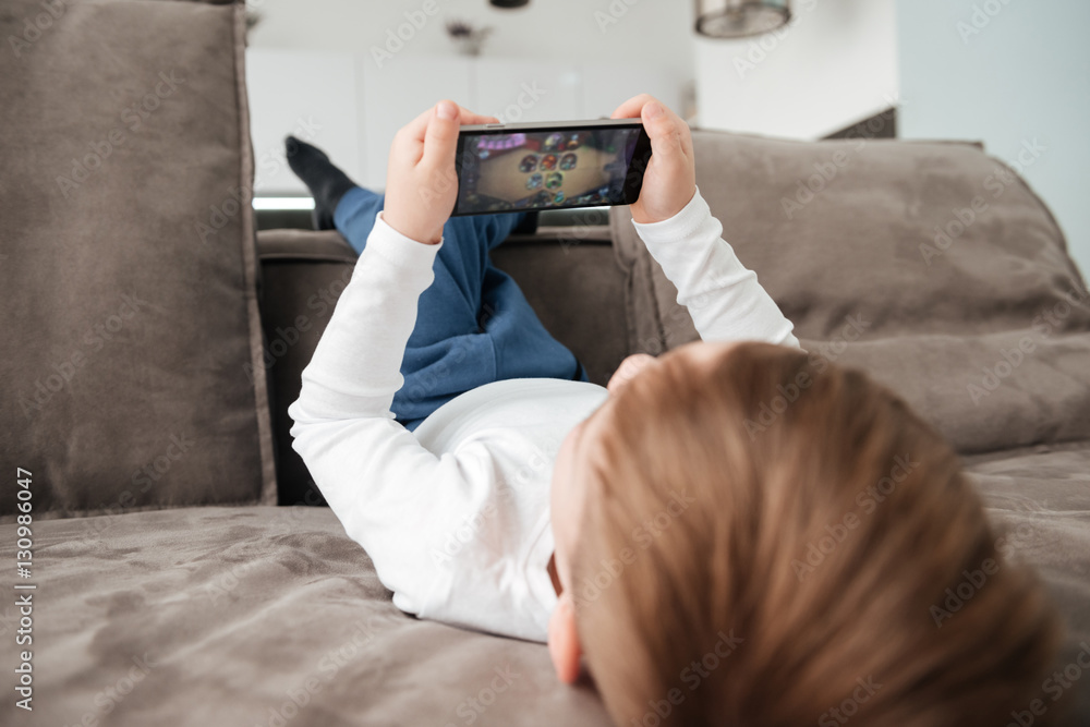 Back view picture of little boy holding smartphone Back view picture of little boy holding smartphone