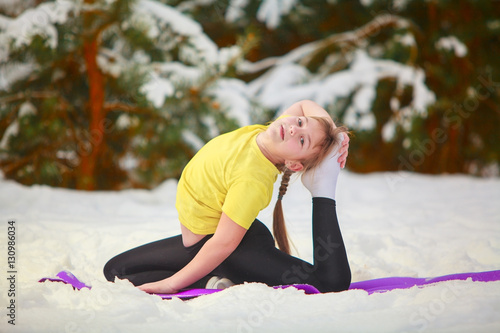 beautiful woman doing yoga outdoors in the snow photo