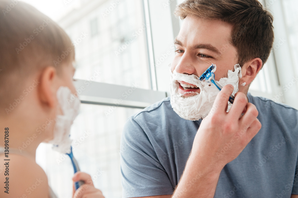 Young father and son shaving in bathroom