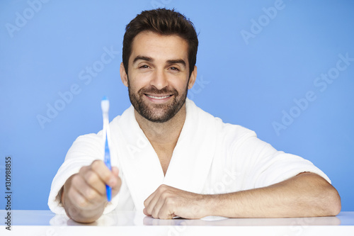 Man in bathrobe holding toothbrush, portrait