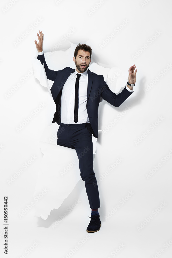 Businessman breaking through backdrop, portrait Businessman breaking through backdrop, portrait