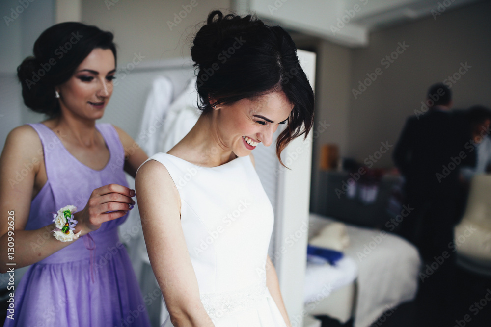 The bridesmaid helping to wear a dress for bride Stock Photo Adobe Stock