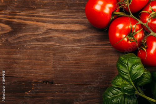 Italian food background with vine tomatoes and basil leaves Ingredients on dark wooden rustic background Copy space Top view