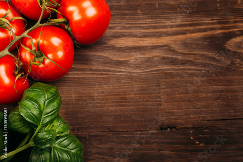 Italian food background with vine tomatoes and basil leaves Ingredients on dark wooden rustic background Copy space Top view
