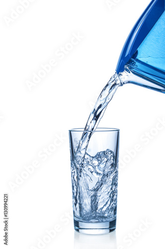 Pouring water from filter mug into glass on white background