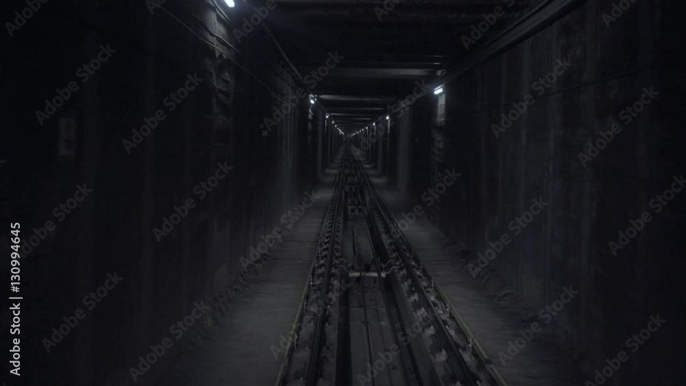 Pov view from underground train moving through dark horror narrow tunnel with cold dimmed laps on walls. Steel rope pulling mechanism seems on floor between rails. Looped video Pov view from underground train moving through dark horror narrow tunnel with cold dimmed laps on walls. Steel rope pulling mechanism seems on floor between rails. Looped video