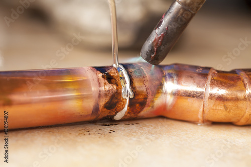 soldering copper pipes with tin and torsh photo