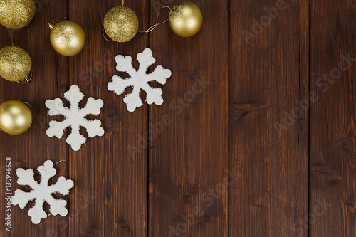 Gold christmas balls and snowflakes decoration on wooden background