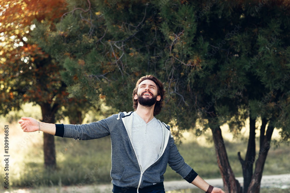 Smiling man enjoying wind blowing in forest. Happy man feeling joy while walking at nature, free space on green trees background. Life love, joy, fresh air, renovation concept foto de Stock |