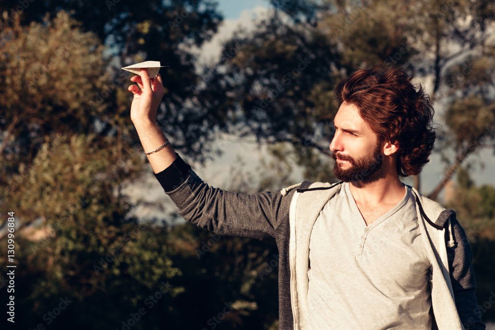 Profile of man running paper airplane in park. Bearded stylish guy playing with handmade paper plane, Leisure, pastime, entertainment concept Profile of man running paper airplane in park. Bearded stylish guy playing with handmade paper plane, Leisure, pastime, entertainment concept