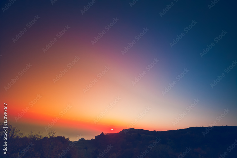 Obraz premium Beautiful summer landscape in the mountains with the sun at dawn. Colourful blue orange pink sky. Natural background