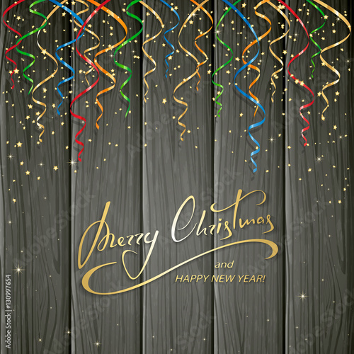 Christmas greeting and colorful tinsel on black wooden backgroun