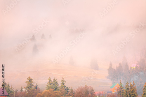 Foggy autumn landscape at mountain valley. Dramatic and picturesque morning scene. Vintage toning effect. Carpathians, Ukraine, Europe.