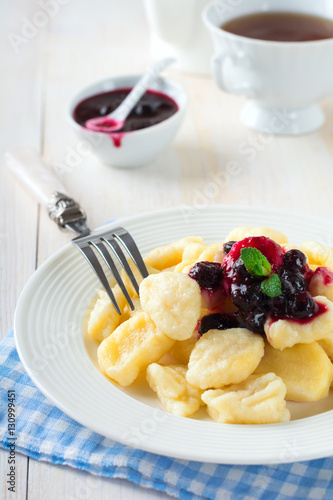 Cheese dumplings,gnocchi with sauce of black currants in a white ceramic plate for a healthy breakfast. Selective focus.