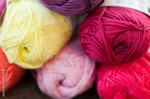 Different types of pink and purple yarn on a wooden background