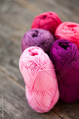 Different types of pink and purple yarn on a wooden background