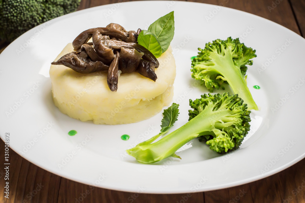 Mashed potatoes with mushrooms and boiled broccoli sauce. Wooden background. Top view. Close-up Mashed potatoes with mushrooms and boiled broccoli sauce. Wooden background. Top view. Close-up