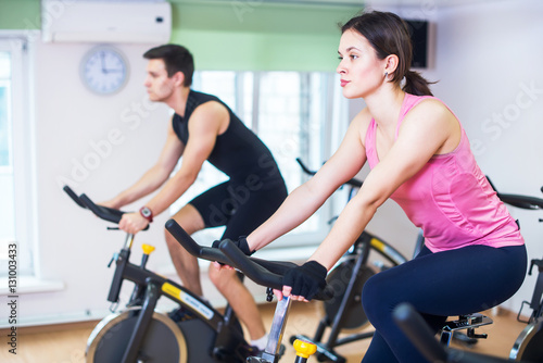 Fototapeta Naklejka Na Ścianę i Meble -  Group training people biking in the gym, exercising legs doing cardio workout cycling bikes