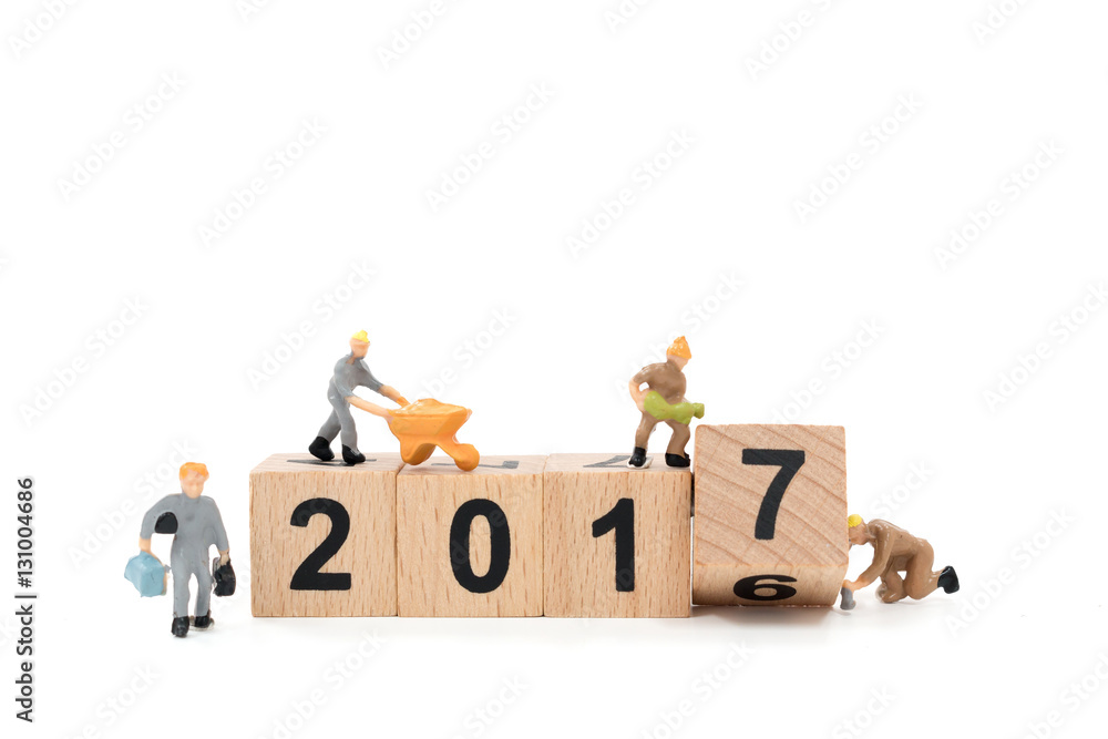 Miniature worker team building wooden block number 2017 on white background