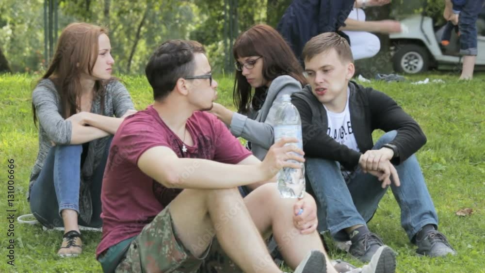 The company of friends on a picnic, guy drinking bottled water The company of friends on a picnic, guy drinking bottled water